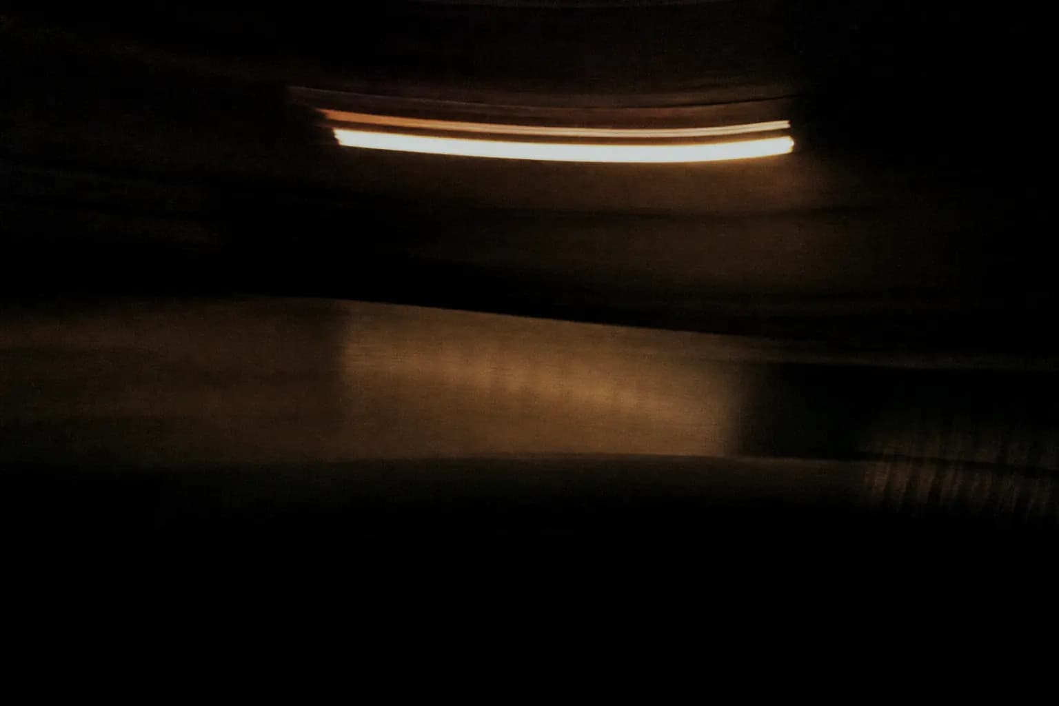 Long-exposure photograph of a panelled meeting room, a desk lamp swept into a curved amber trail.