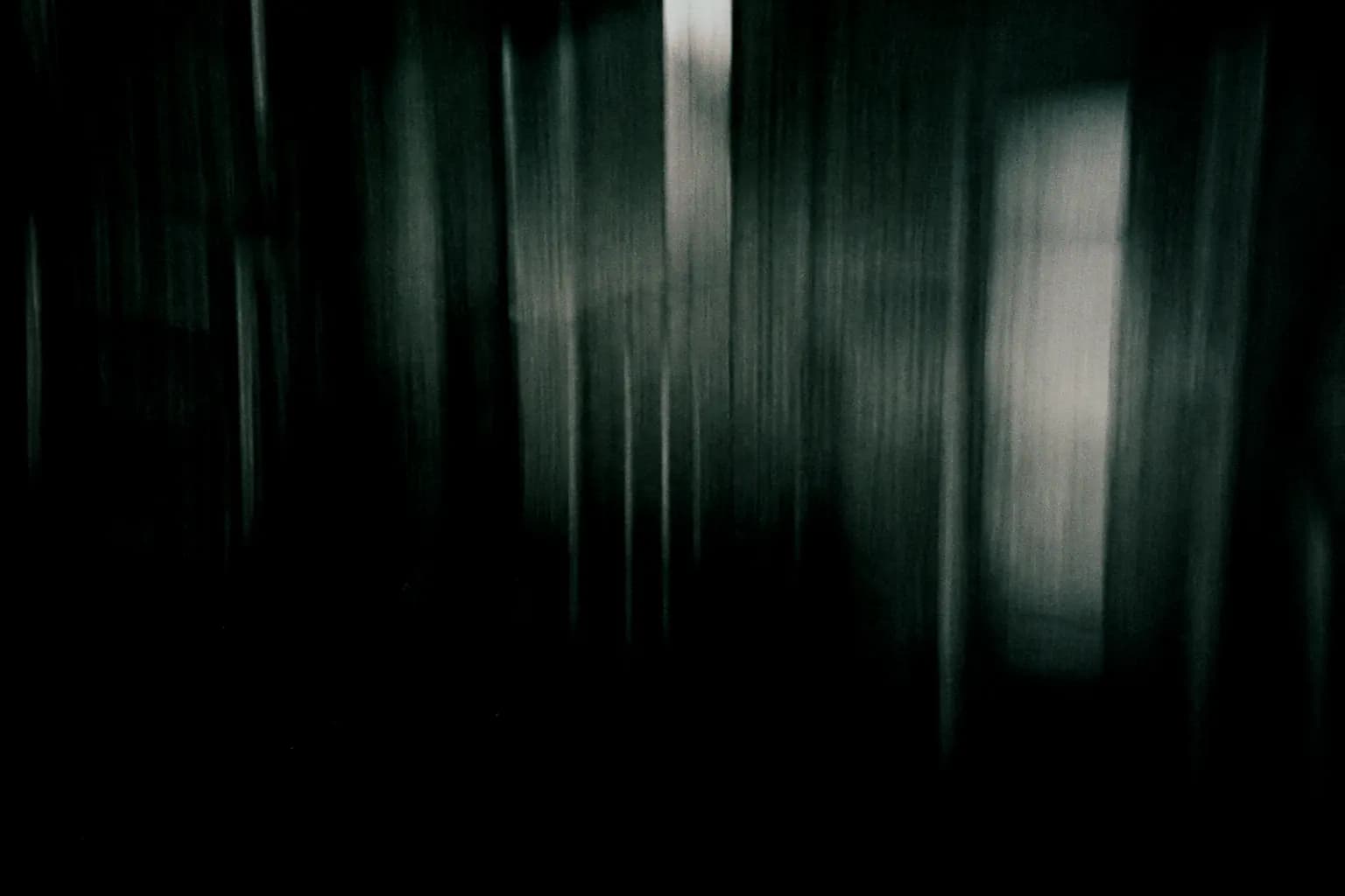 Long-exposure photograph of a machine hall dissolved into vertical grey-green streaks.