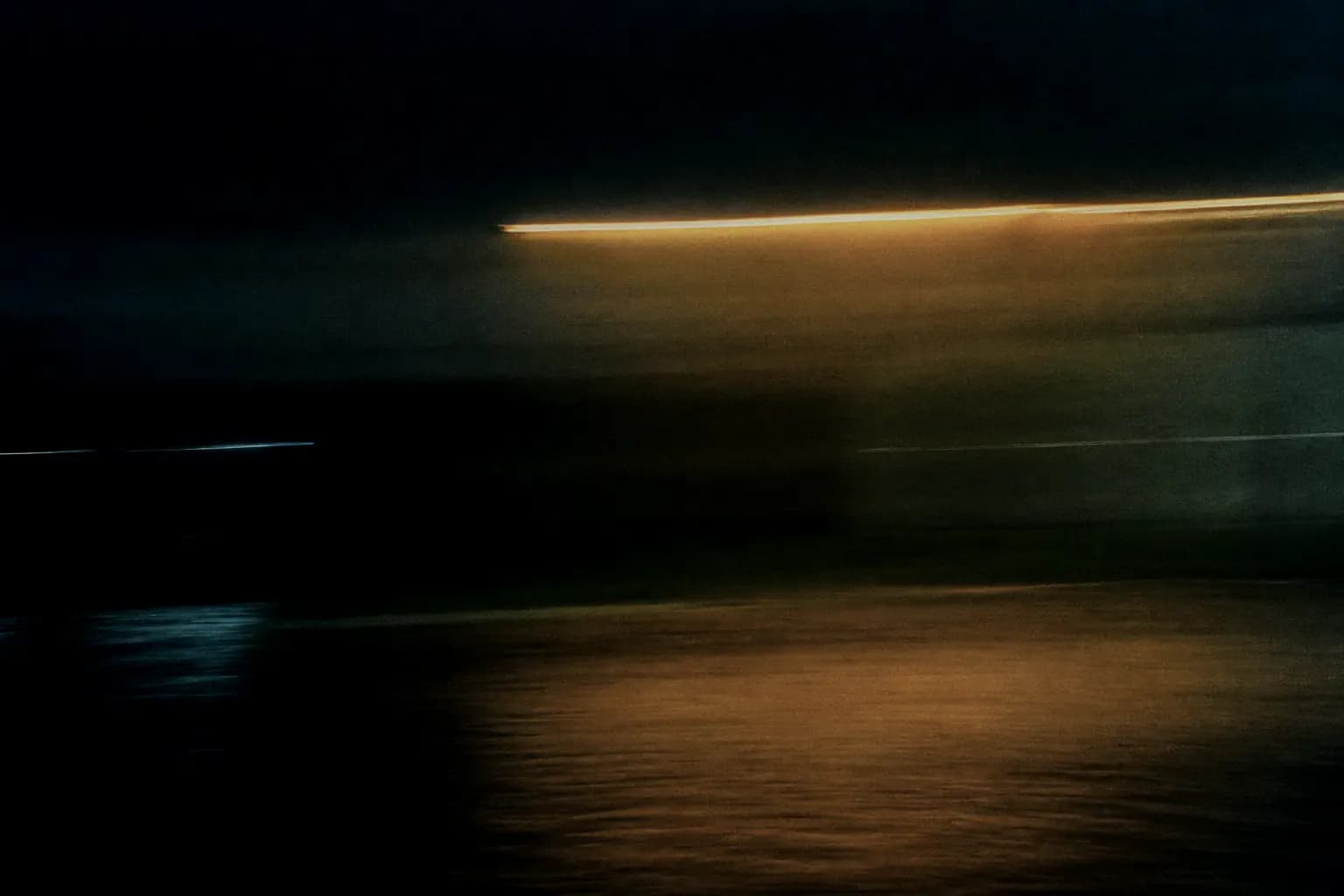 Long-exposure photograph of a works yard at night, a single lamp drawn into an amber streak.